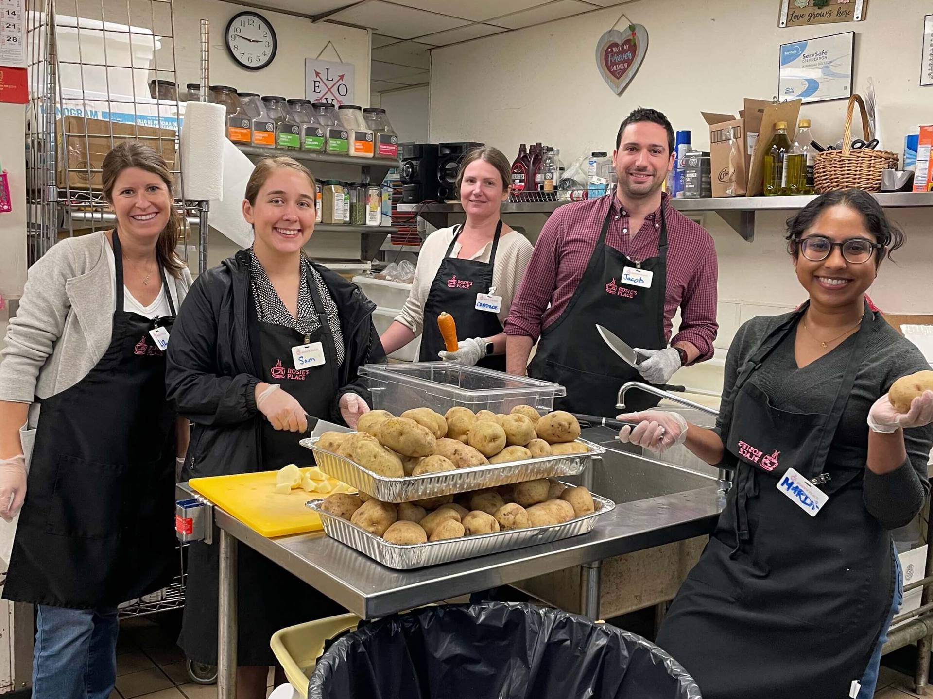 A group of volunteers in a kitchen, engaged in preparing meal, highlighting a warm and communal atmosphere.