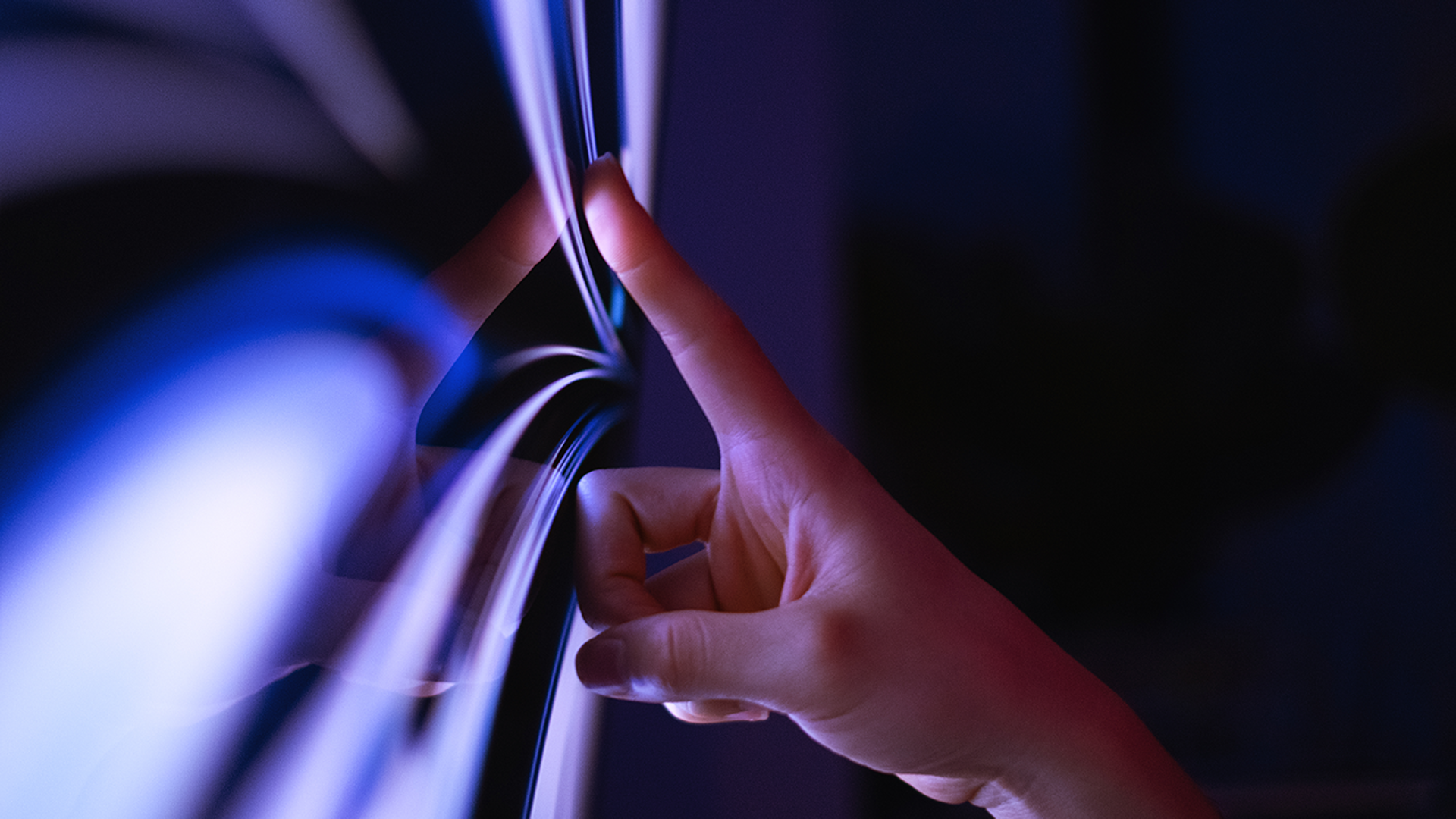 A close-up of the interaction between persons hand and a large touch screen display.