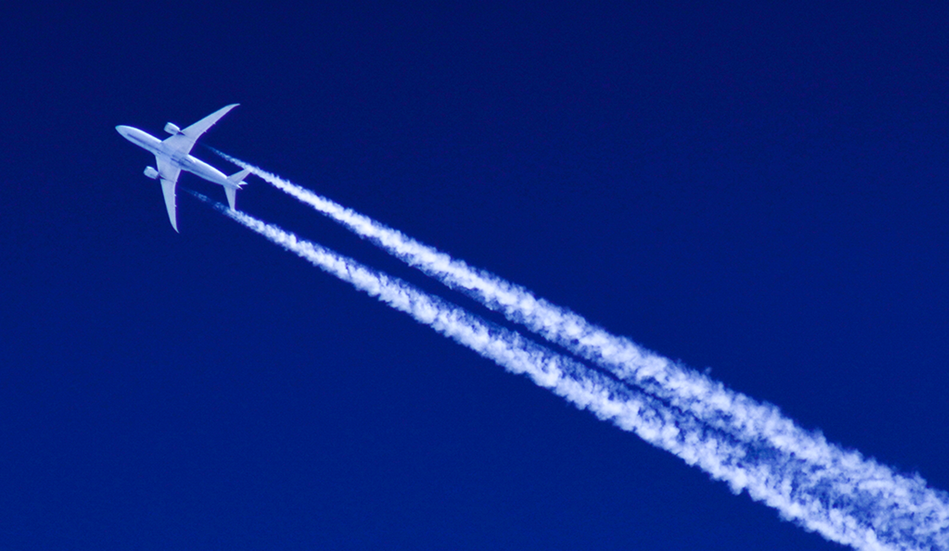 A jet aircraft ascends in the sky, creating a visible contrail as it moves swiftly through the atmosphere.