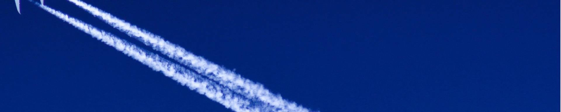 A jet aircraft ascends in the sky, creating a visible contrail as it moves swiftly through the atmosphere.